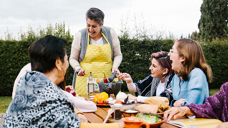 Group of happy people eating lunch at a picnic table at a park