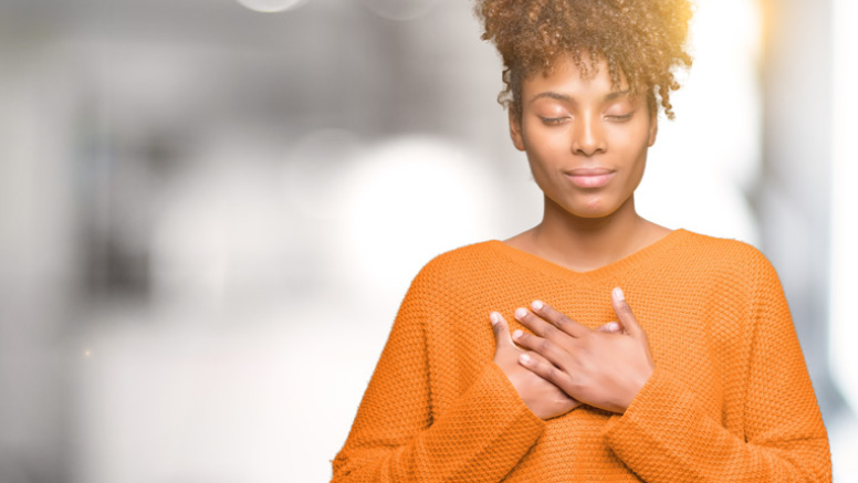 Woman with closed eyes and gentle smile, with hands on heart