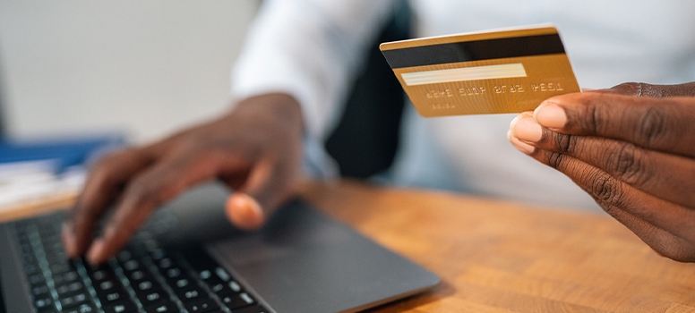 Man's hands holding credit card at laptop