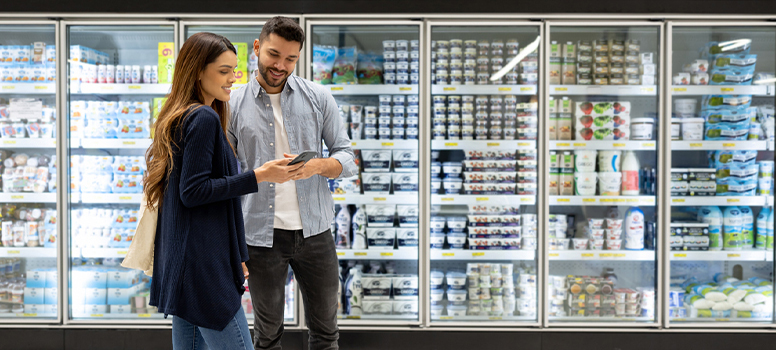 Couple in dairy section of store looking at list to avoid impulse buying