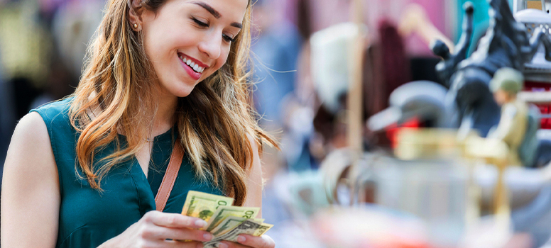 smiling woman counting cash and looking at antiques