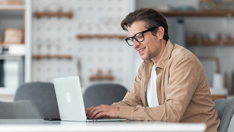 Man, sitting at table in front of laptop, making debt resolution deposits