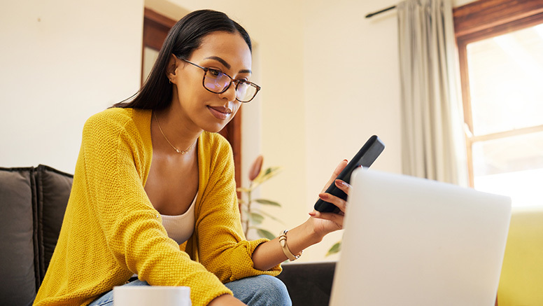 Content woman at home on phone and laptop, adjusting debt resolution deposits