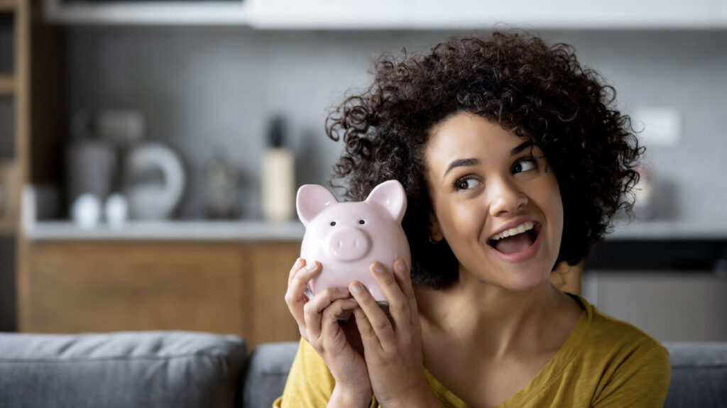 Woman smiling holding piggybank demonstrating savings challenges