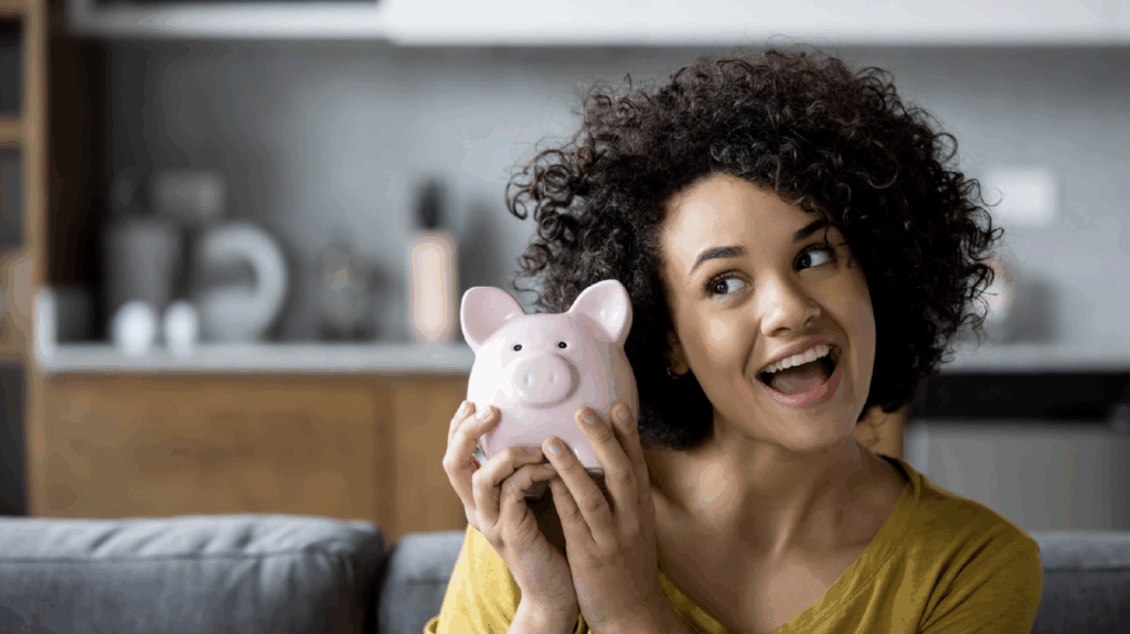 Woman smiling holding piggybank demonstrating savings challenges