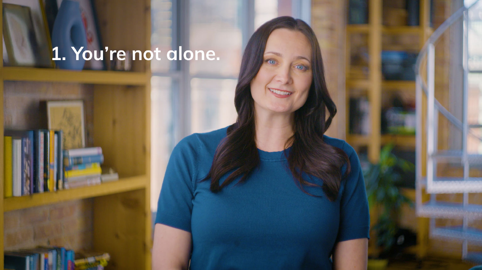Dr. Erika Rasure smiles next to the tip "You're not alone" in Navigating Shame About Debt video