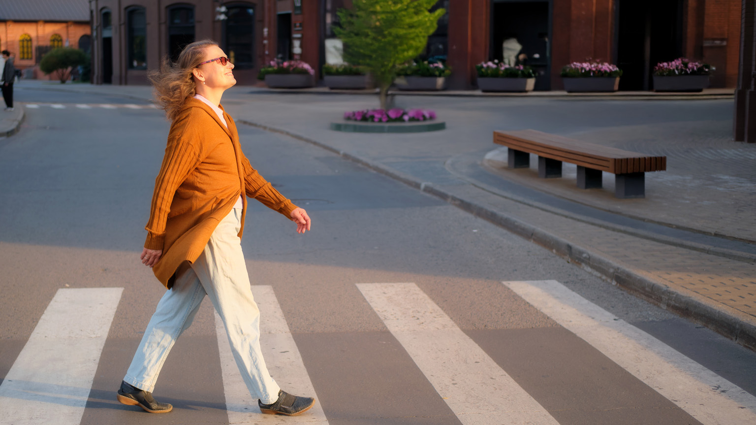 Confident woman walks across a street smiling representing money and your future self