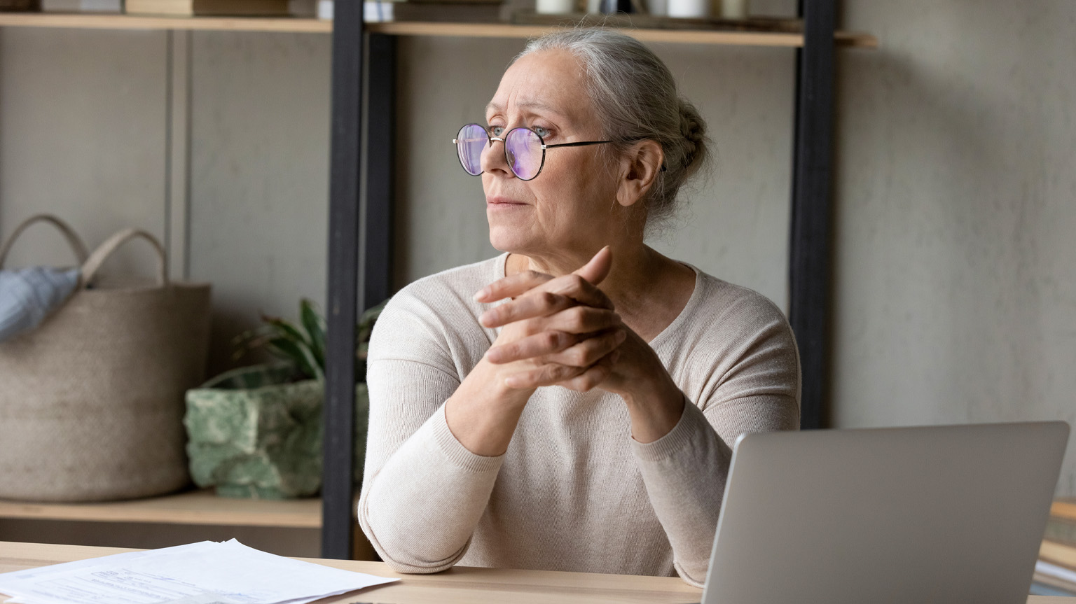 Woman with bills and laptop looking concerned representing financial grief