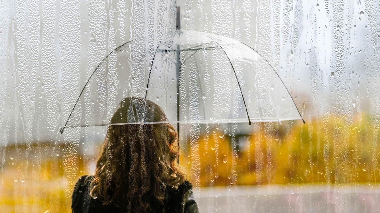 Woman holding an umbrella in the rain representing weathering financial storms