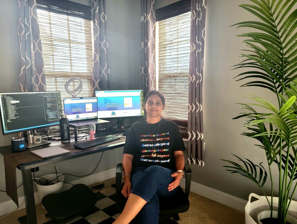 Sonam smiling at camera in front of at-home set-up with three screens